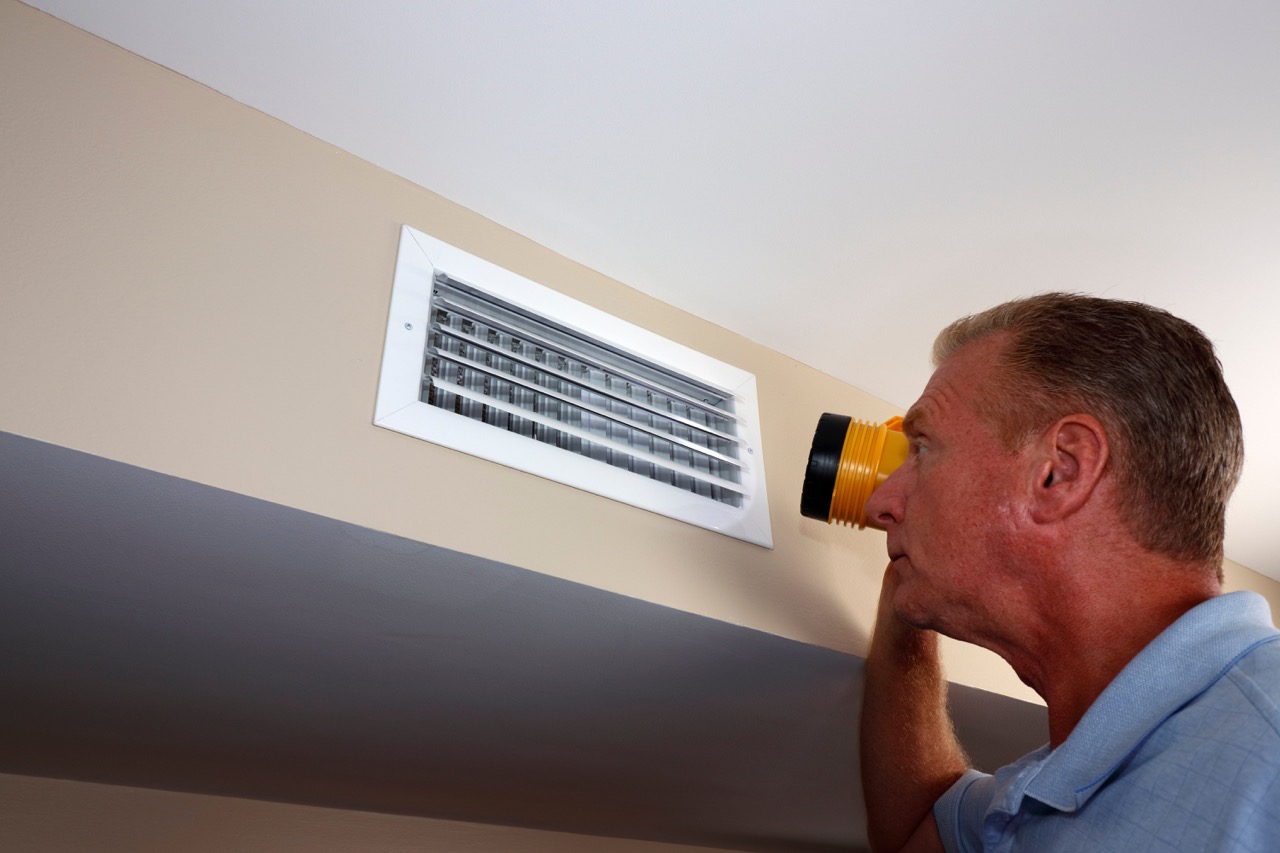 Man inspecting a home's air vents
